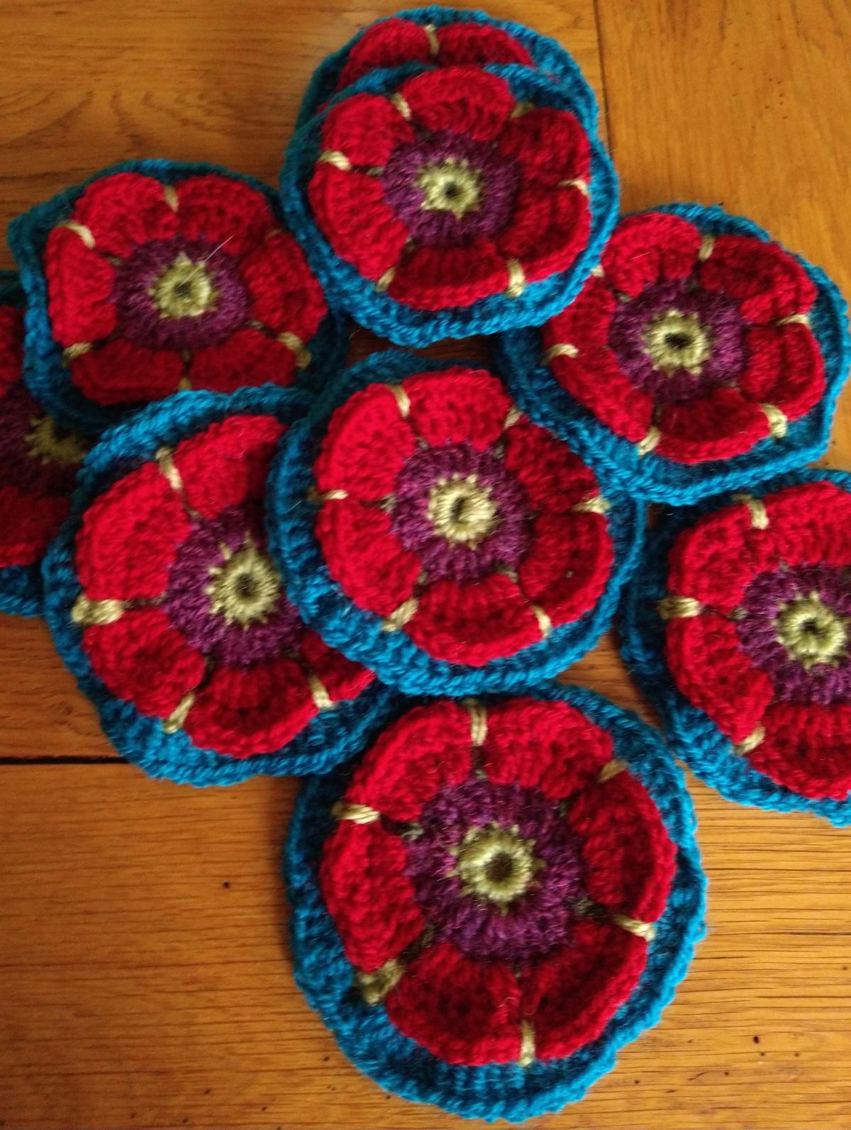 Poppy design crochet flowers, part of a Jane Crowfoot Fields of Gold design 
They have green centres with red petals and a blue edge 
